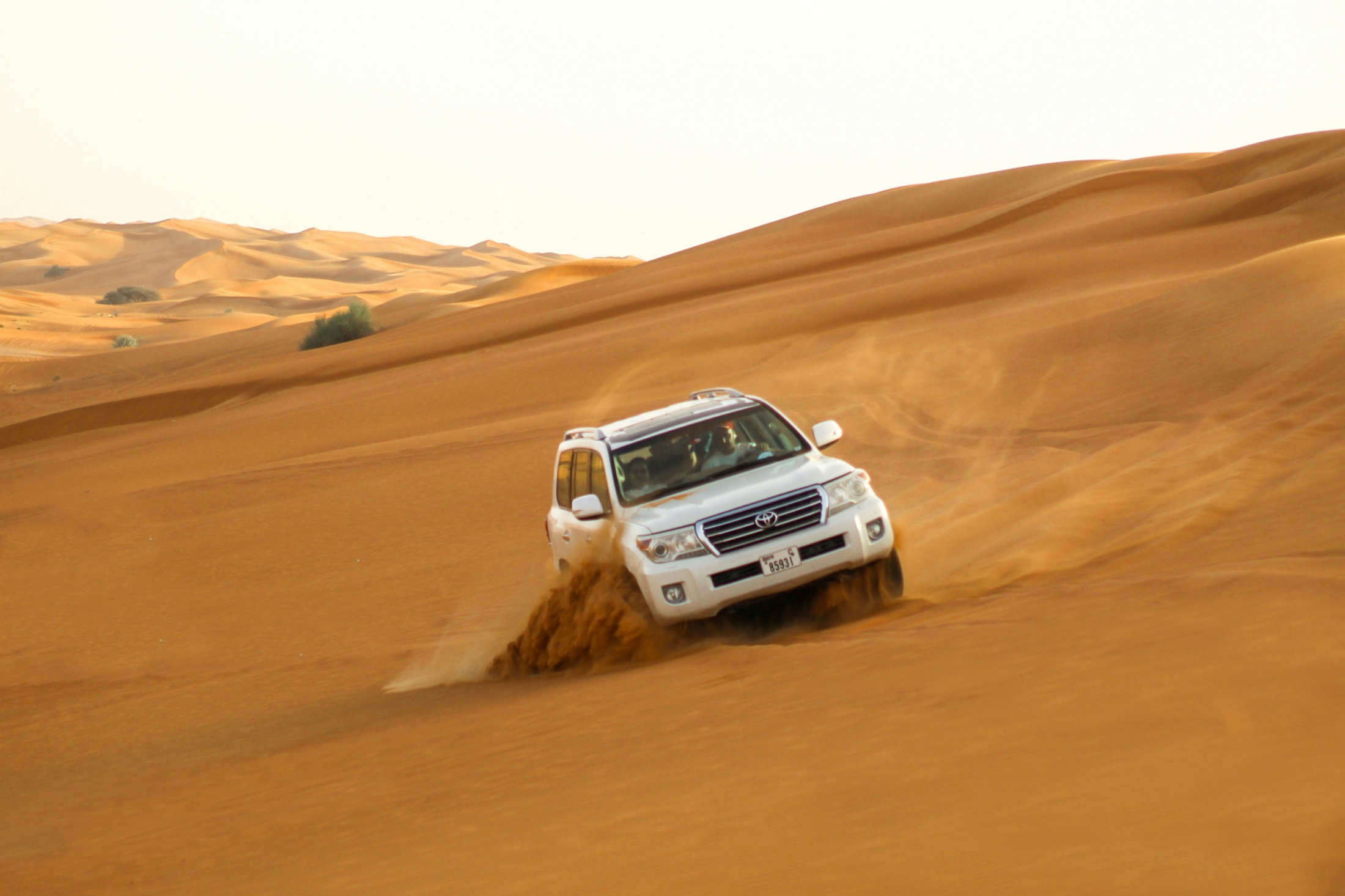 A four-wheel-drive vehicle crossing desert dunes